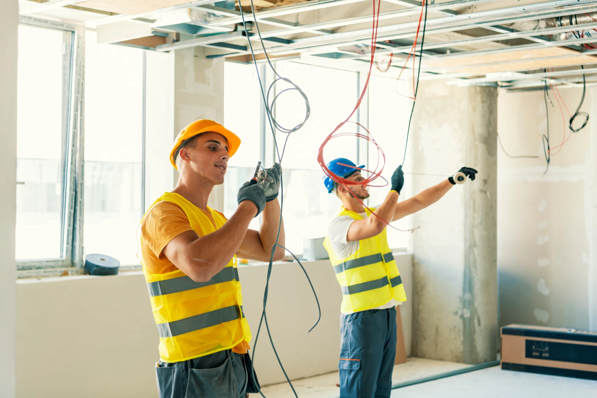 Two electricians first-fixing cables on a commercial site